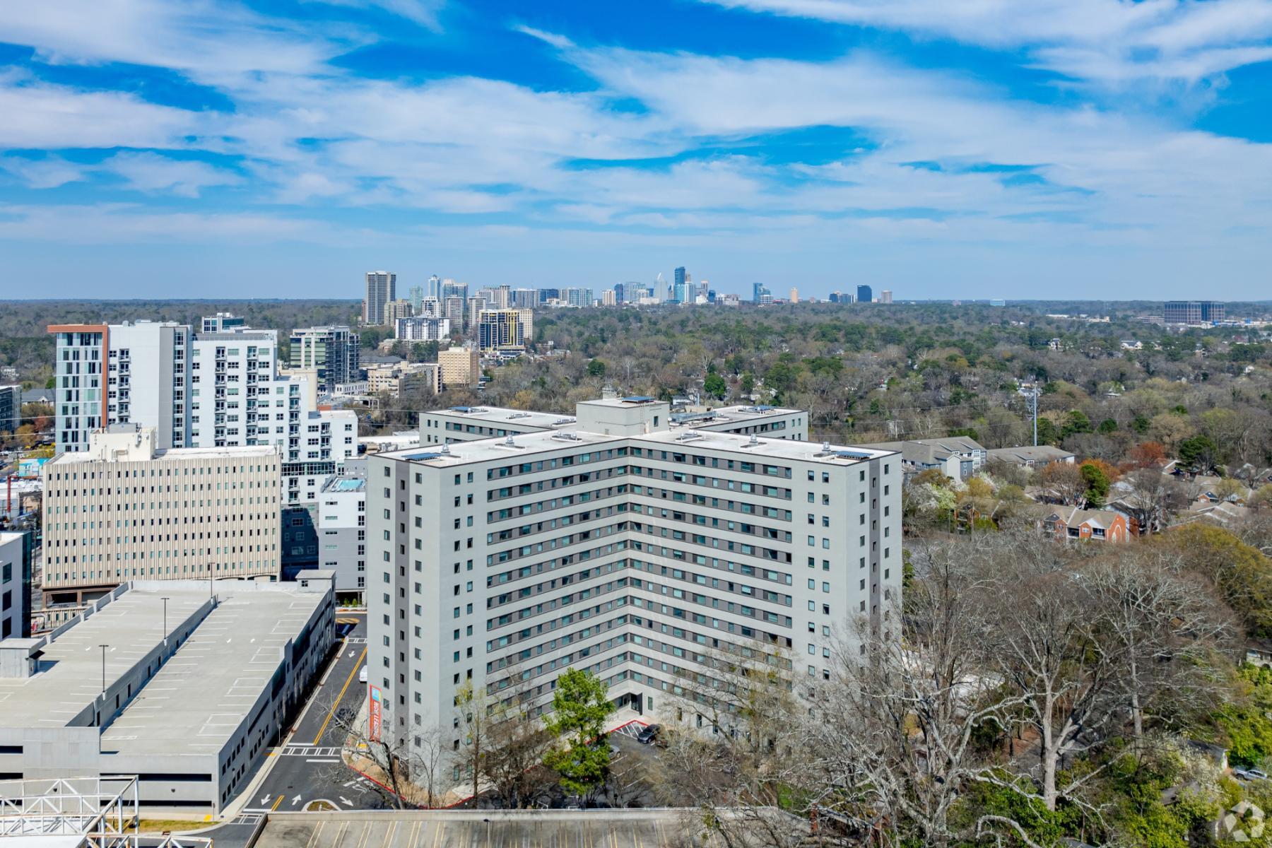 Aerial drone view of The Lofts at Twenty25 high-rise on Peachtree Road in Buckhead Atlanta, showcasing the historic 16-story building and Midtown skyline.